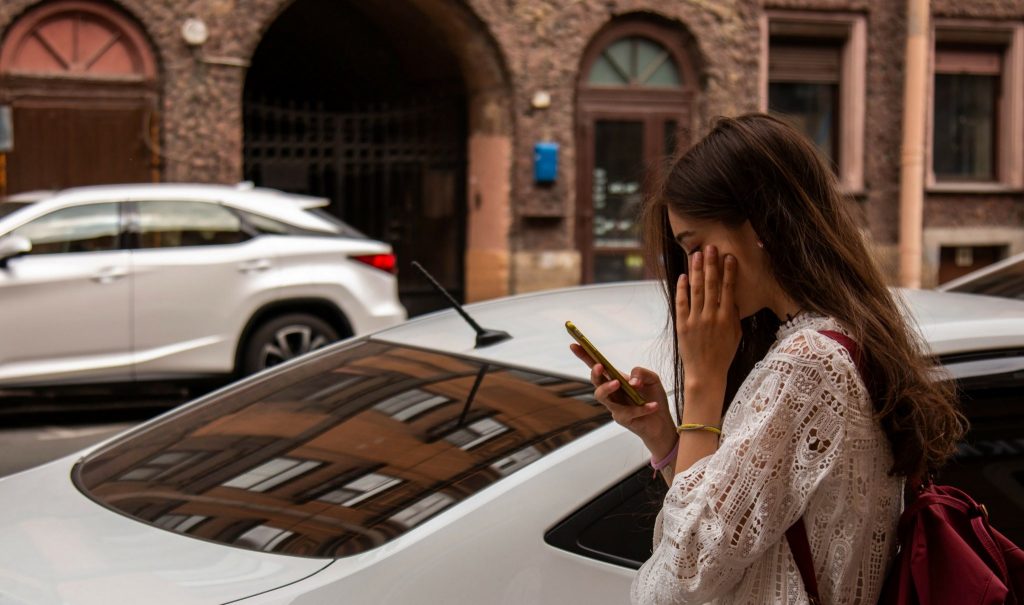 Woman looks at phone on street.