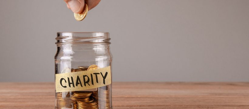 A jar marked 'Charity' holding gold coins.