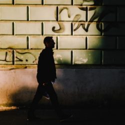 Silhouette of a man walks down a side street.